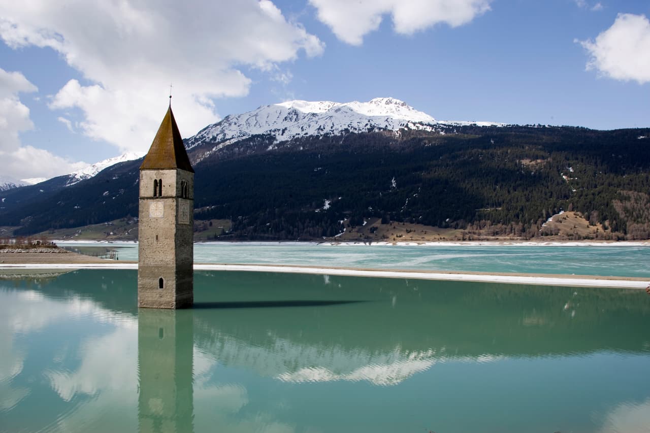 El lago Resia, en Los Alpes italianos, es conocido por un campanario que emerge de sus aguas heladas. En 1950 se inundó una área cercana a la frontera entre Italia, Austria y Suiza para la construcción de una represa. Curon, un pequeño pueblo que fue alguna vez hogar de cientos de personas, quedó sumergido y solo su campanario quedó por encima de la superficie del agua.