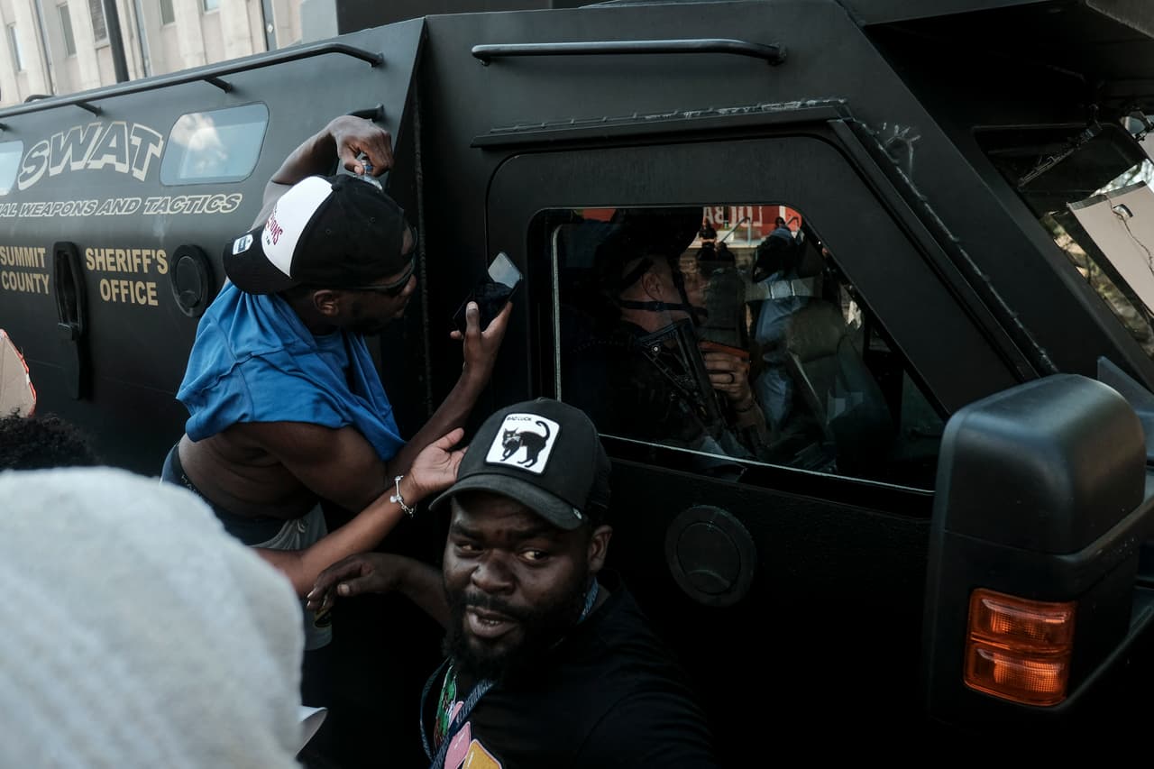 Manifestantes hacen gestos groseros a un vehículo blindado del Sheriff de Akron mientras se reúnen frente al Ayuntamiento para protestar por la muerte de Jayland Walker.