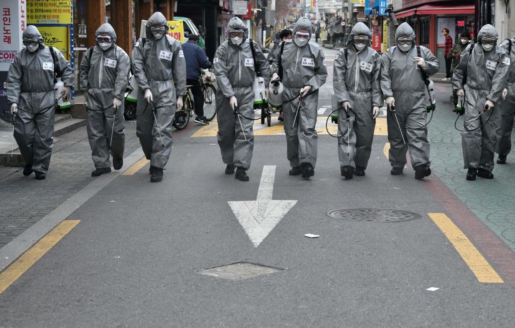 Soldados surcoreanos ataviados con trajes protectores rocían desinfectante por una calle de Seúl.