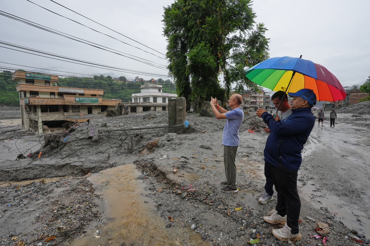Personas de otras zonas graban con sus teléfonos móviles los daños causados por las inundaciones repentinas en el distrito de Nuwakot, Nepal, el sábado 29 de agosto de 2026. (Foto AP/Rajesh Kumar Singh)