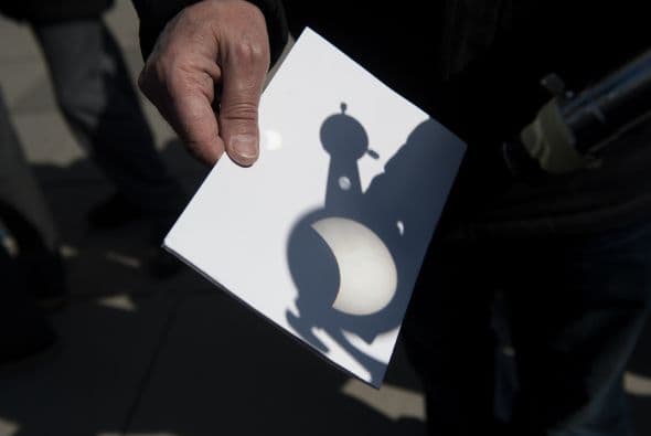 Aquí un hombre utilizando un telescopio para proyectar la imagen del eclipse solar sobre un papel en Pristina, Kosovo.