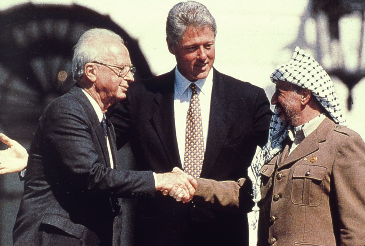 American President Bill Clinton watches as the Israeli Prime Minister Yitzhak Rabin (1922 - 1995) shakes hands with the Palestinian leader Yasser Arafat in the garden of the White House after the signing of the deal transferring much of the West Bank to Palestinian control. (Photo by MPI/Getty Images)