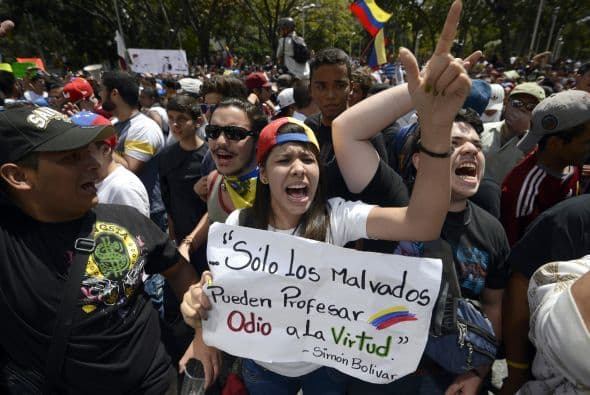 Los estudiantes desarmados gritan consignas durante una manifestación pacífica contra el régimen del mandatario Nicolás Maduro el 12 de febrero de 2014. Motorizados uniformados y con sus caras cubiertas, dispararon contra los manifestantes, matando a dos estudiantes y a un oficial.