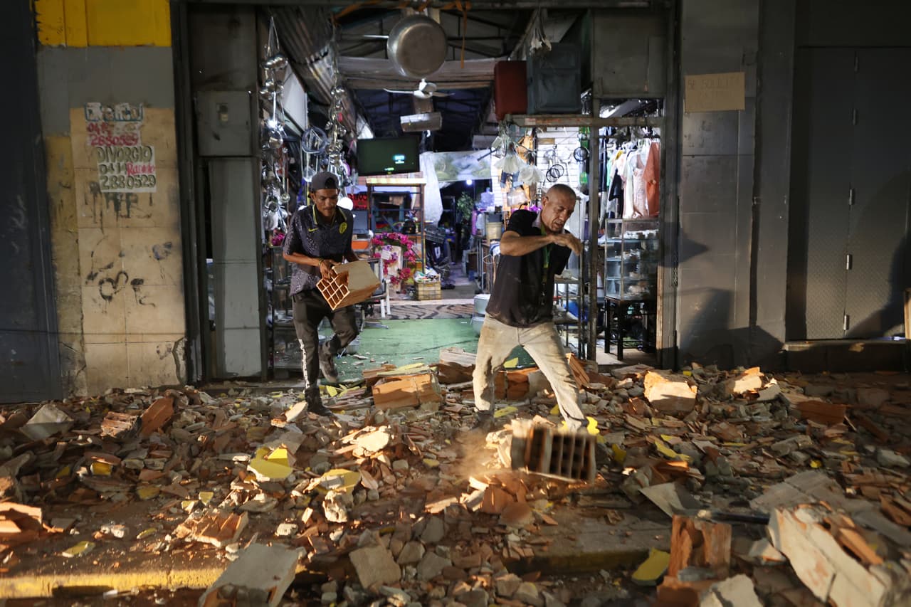 Hombres caminan entre los escombros tras un terremoto en Caracas.
