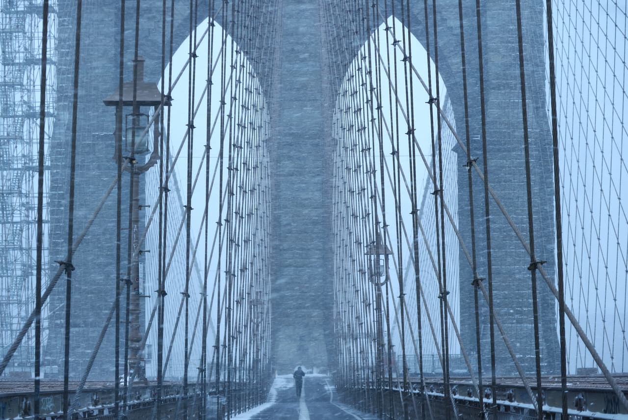 Una persona camina por el puente de Brooklyn durante la nevada.