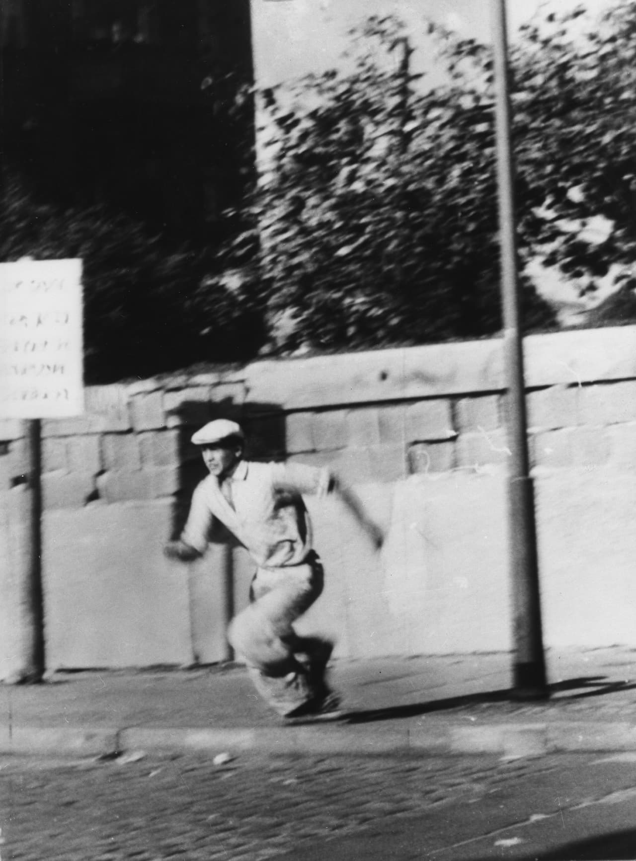 Luego de la derrota de los Nazis al finalizar la segunda guerra mundial, Alemania fue dividida entre la Unión Soviética y los Aliados. En Alemania Oriental, el lado soviético de la división, se aplicaron los controles económicos del comunismo mientras que en Alemania Occidental se mantuvo la economía del libre mercado, como en los países Aliados. Una barrera física tuvo que ser instalada por Alemania oriental para evitar que sus ciudadanos escaparan al lado occidental de la ciudad. Pero no era suficiente, como se ve en la fotografía donde un alemán oriental se escapa luego de saltar el muro y se refugia en Alemania occidental, el 16 de octubre de 1961.