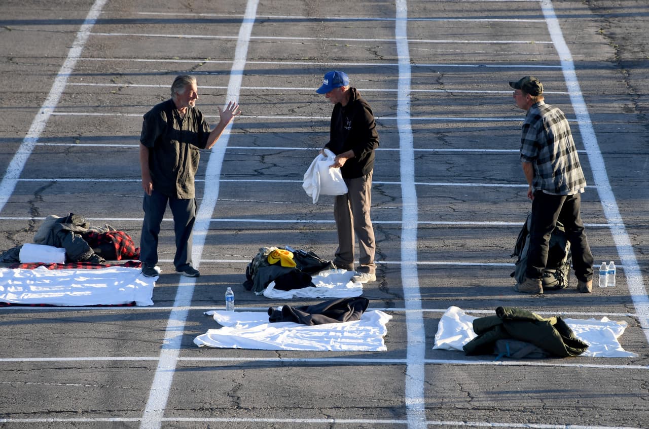 Personas sin hogar llegan a instalarse a un refugio temporal en un estacionamiento en el Cashman Center, el 30 de marzo de 2020 en Las Vegas, Nevada. En el suelo, se ven rectángulos pintados para que mantengan la distancia social recomendada para evitar contagios de coronavirus.