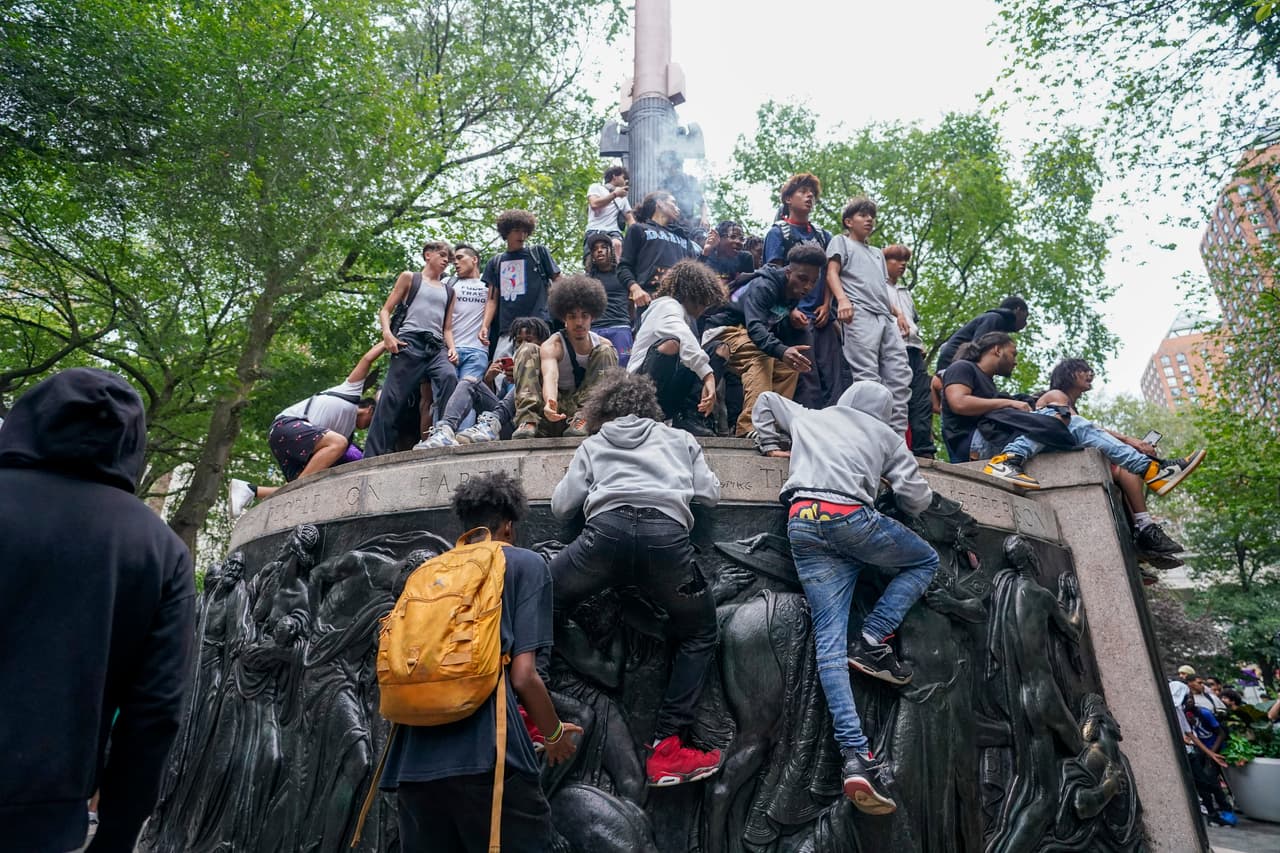 Los jóvenes escalan sobre una escultura pública en medio del desorden en Union Square.