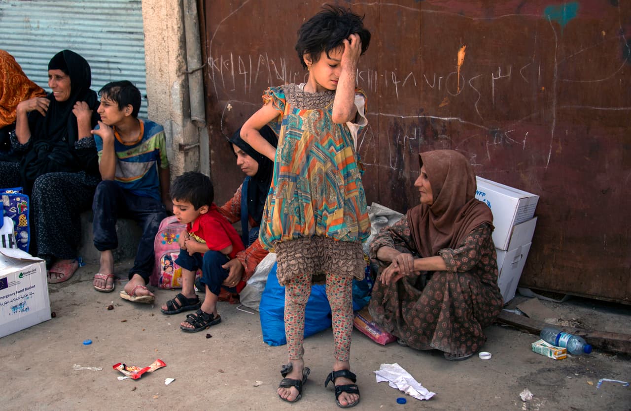 Una niña iraquí, que huyó de la lucha entre las fuerzas gubernamentales y los yihadistas del grupo Islámico (ISIS) en la Ciudad Vieja de Mosul, reacciona mientras está de pie junto a una muralla en el distrito industrial occidental de la ciudad que espera ser reubicada el 8 de julio de 2017.