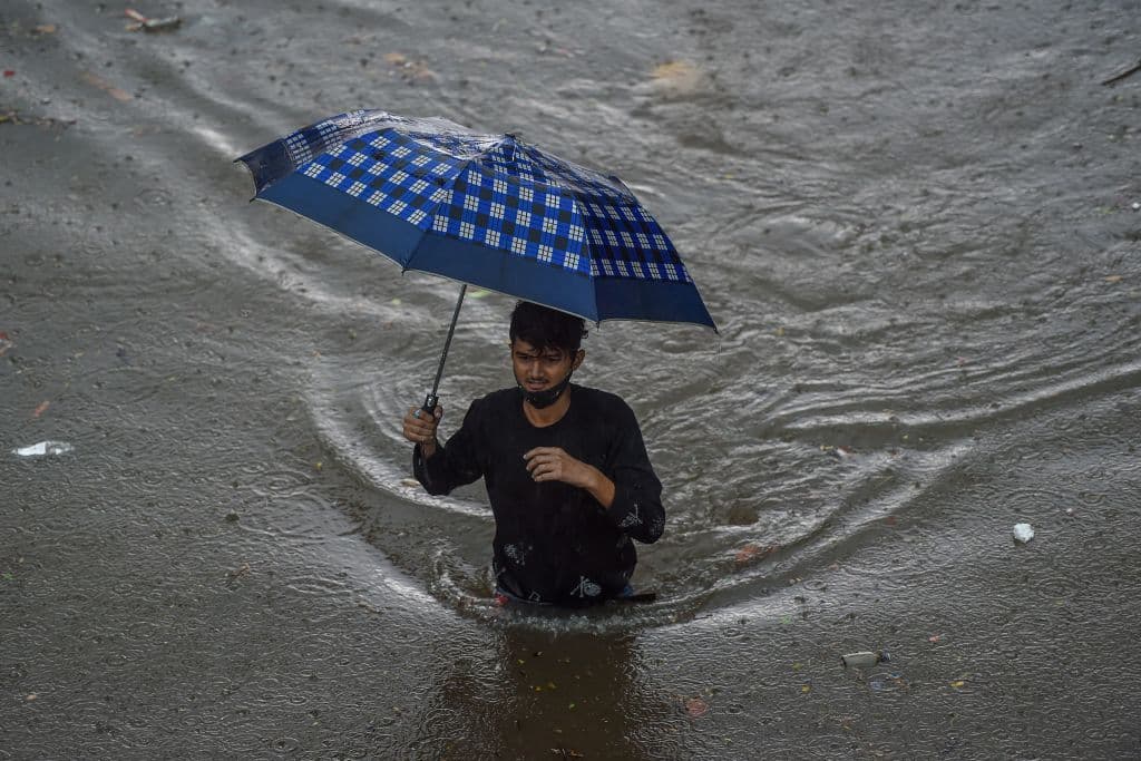 Un hombre camina por una carretera inundada durante las fuertes lluvias monzónicas en Mumbai el 9 de junio de 2021.