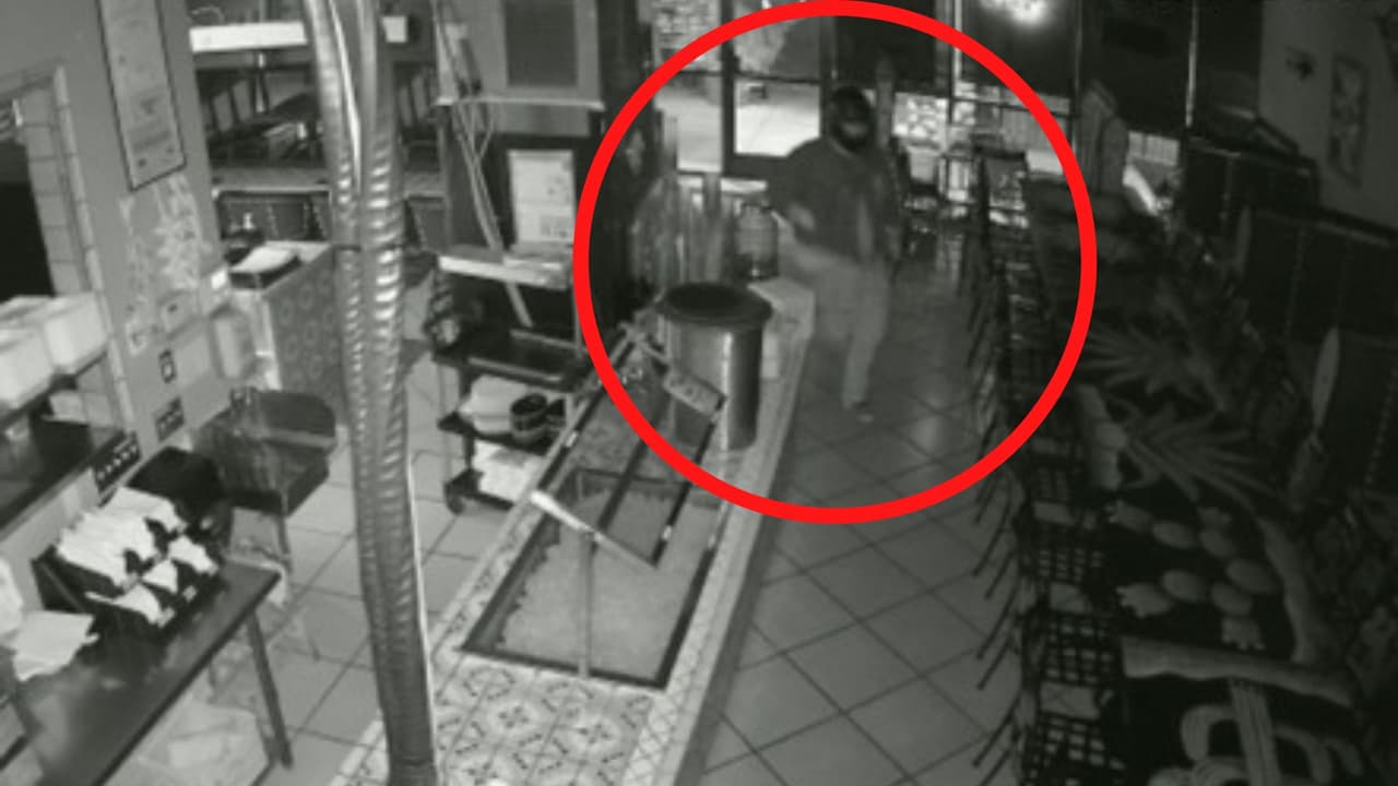 Tras romper el vidrio de la puerta, el ladrón ingresa corriendo al restaurante.