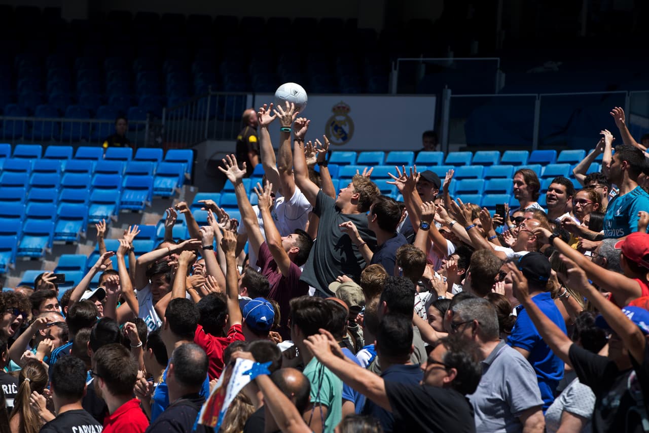 Fans scramble to catch a soccer ball that Alvaro Odriozola kicked into the crowd during his official presentation for Real Madrid at the Santiago Bernabeu stadium in Madrid, Spain, Wednesday, July 18, 2018. Odriozola previously played for Real Sociedad. (AP Photo/Paul White)