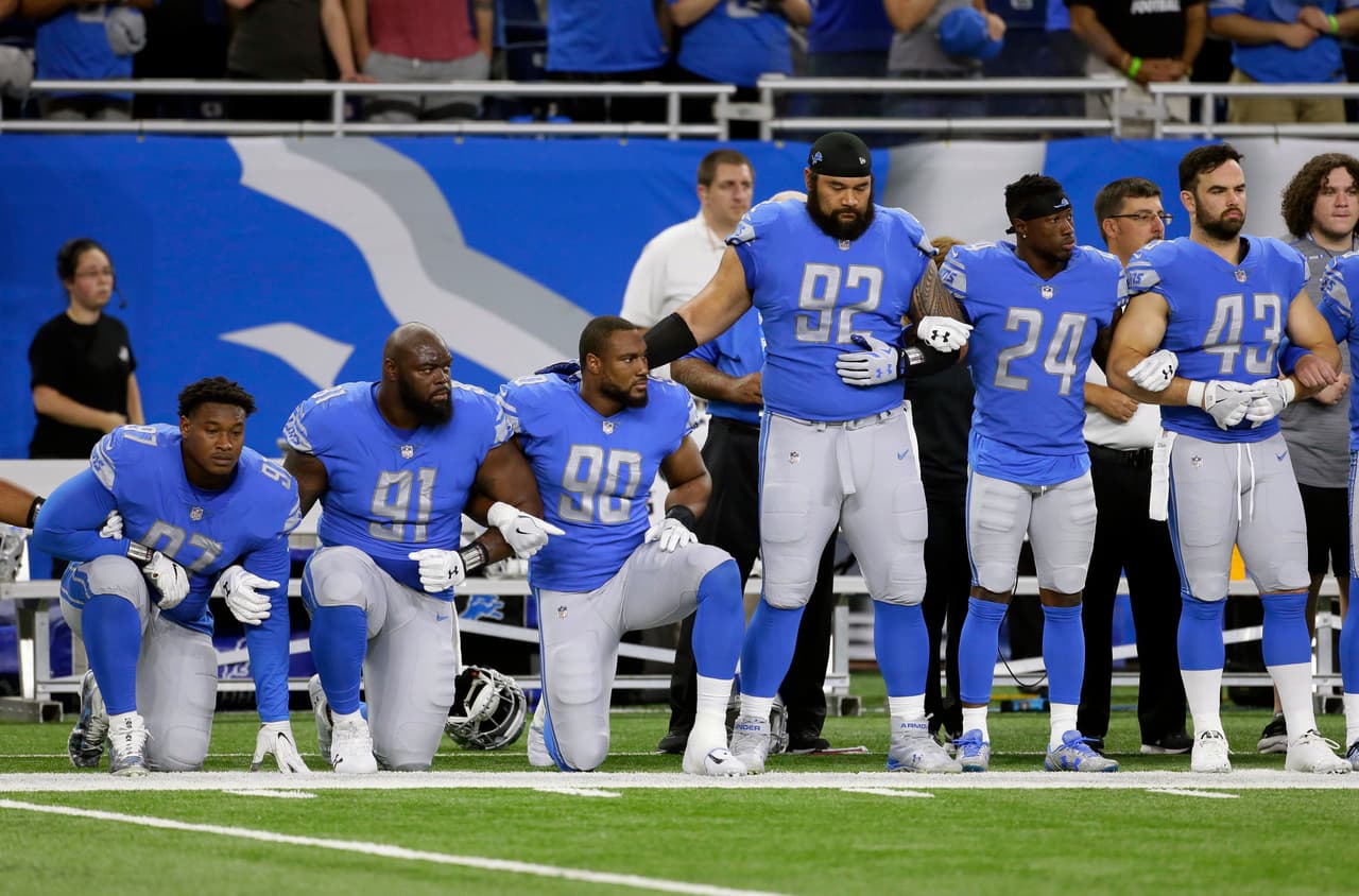Los jugadores defensivos de los Detroit Lions Armonty Bryant (97), A'Shawn Robinson (91) y Cornelius Washington (90) de rodillas durante el himno nacional antes del juego contra los Atlanta Falcons.