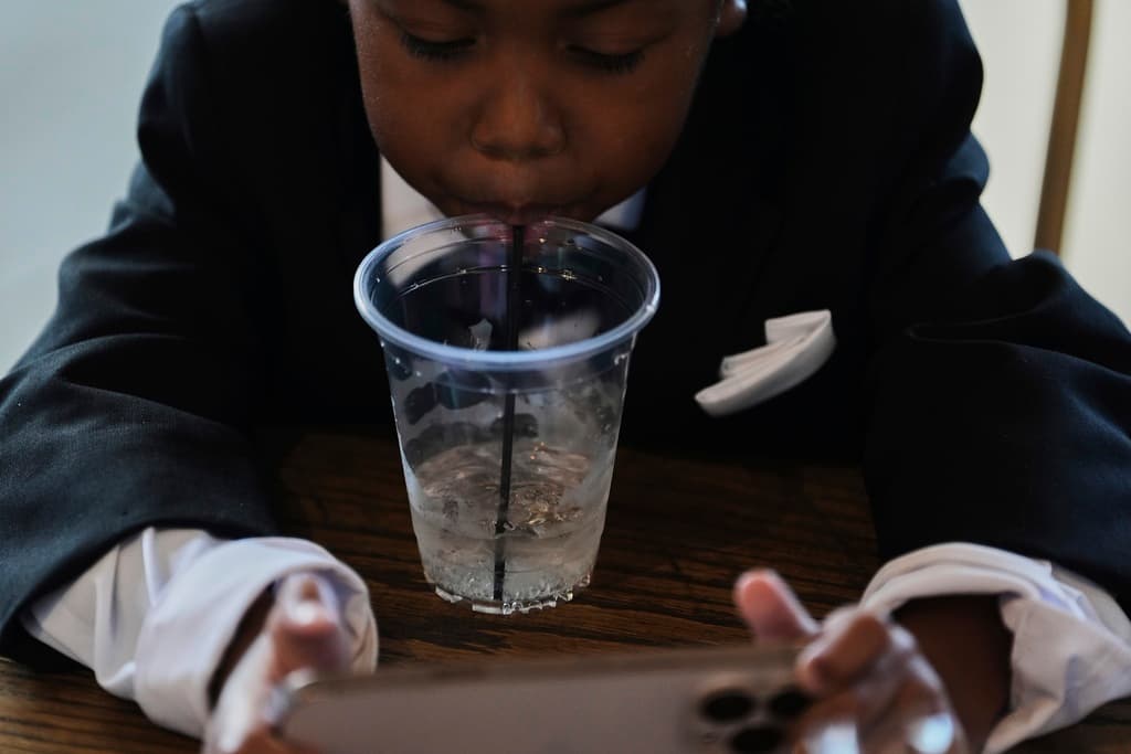 Legend McNeary, de 4 años, toma un sorbo de agua mientras está sentado en el interior entre fotos de la fiesta nupcial antes de una boda el sábado 23 de agosto de 2025 en Newtown, Ohio. (Foto AP/Joshua A. Bickel)