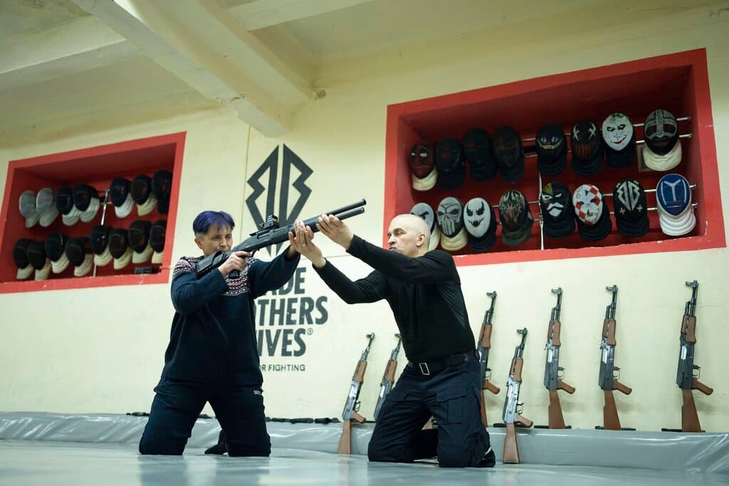 Un instructor muestra a la voluntaria Viktoria Balesina cómo se usa un rifle. Balesina, instructora de tenis de mesa nacida en Kharkiv, es rusoparlante pero ahora solo emplea el ucraniano. Ella forma parte de una docena de mujeres voluntarias que se han alistado en grupos de defensa de la ciudad.