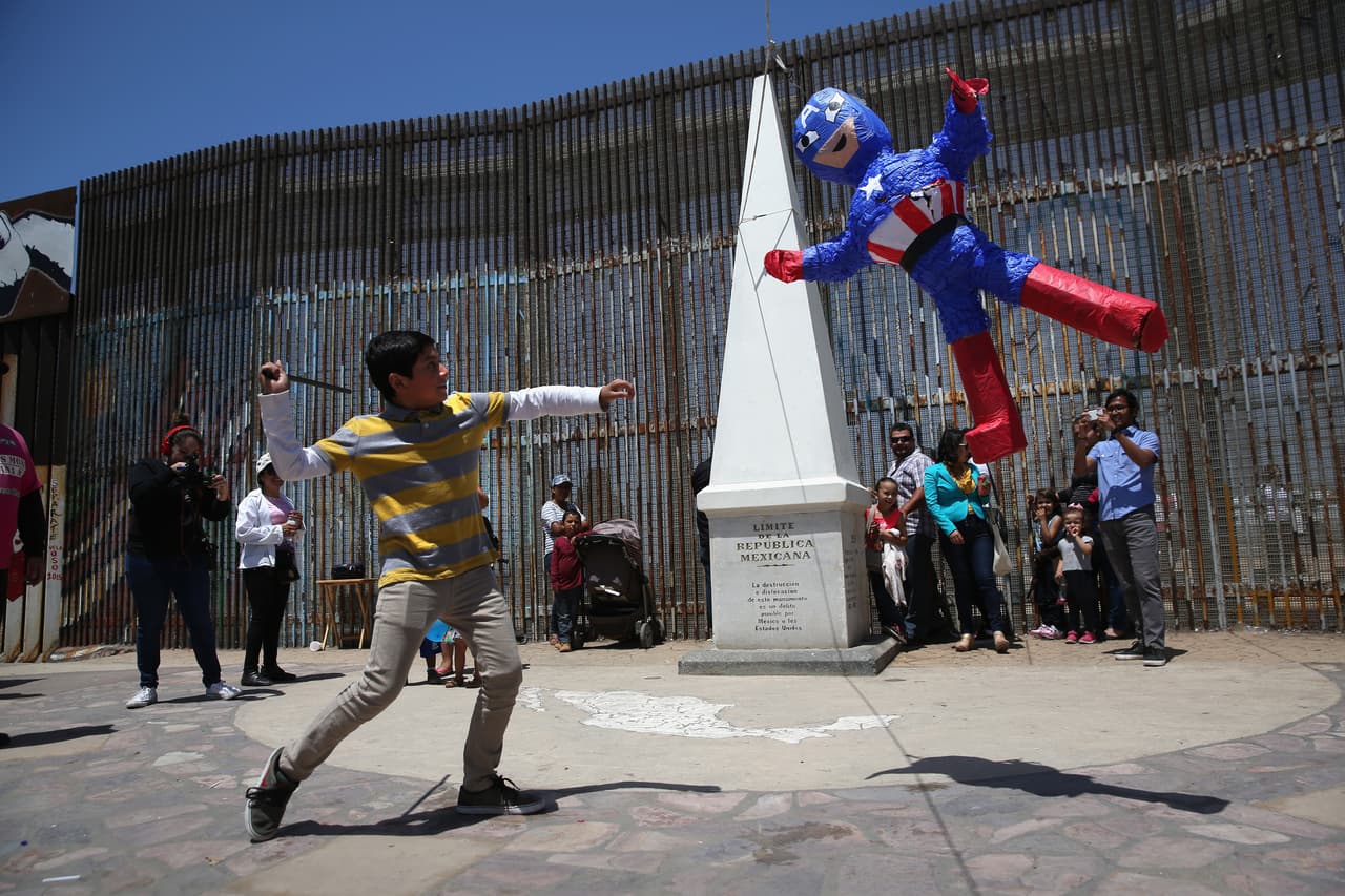 A child takes a swing at a piñata as part of a Children's Day celebration at the border.