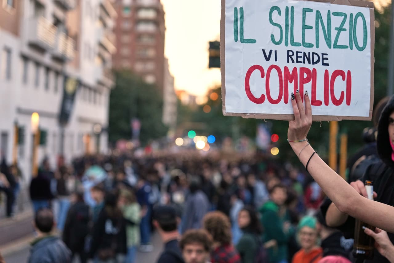 Un manifestante muestra una pancarta en italiano que dice "Tu silencio te hace cómplice" durante una marcha por las calles de Milán, el sábado 24 de octubre de 2026.