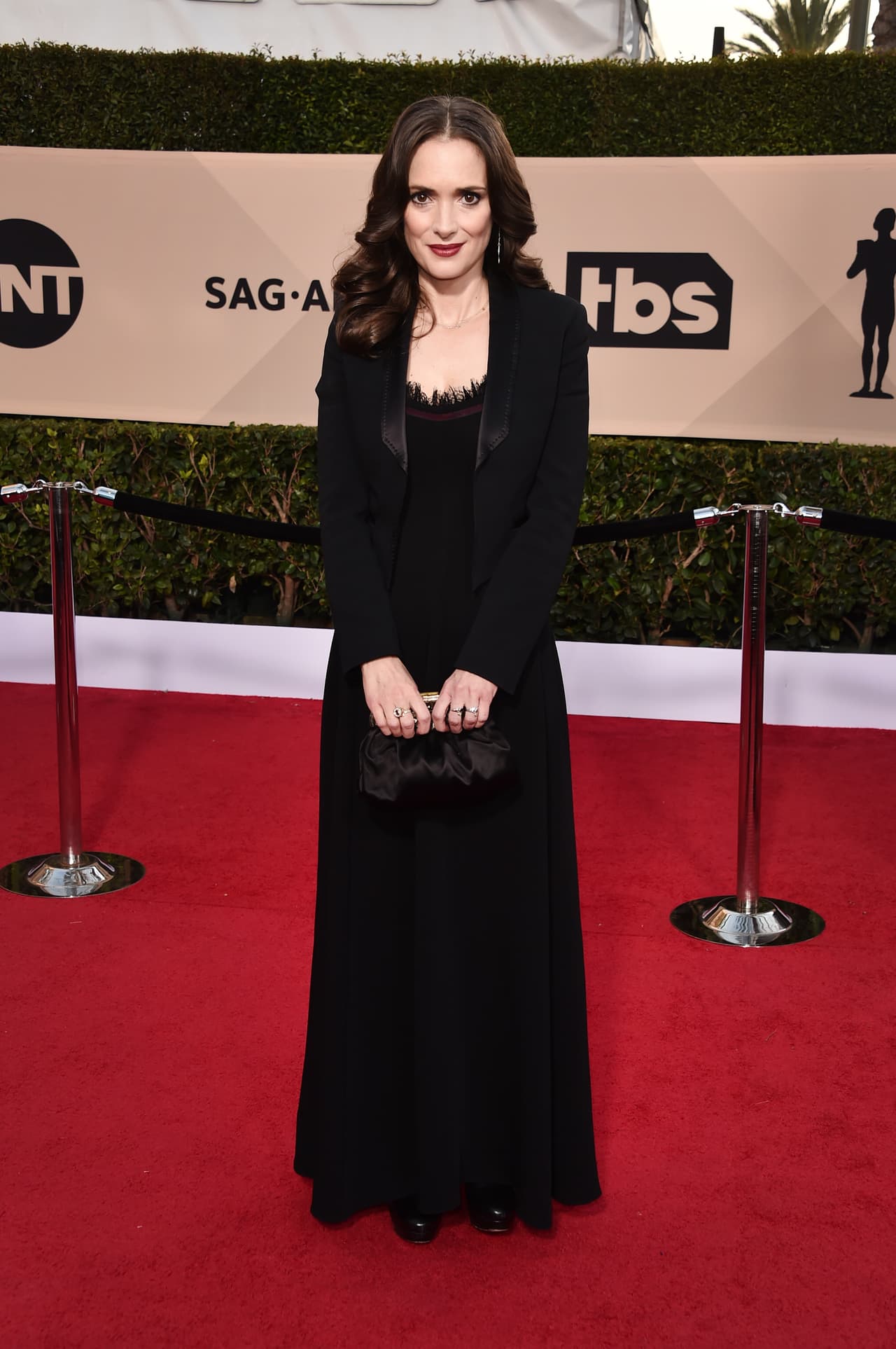 La actriz Winona Ryder eligió vestir un atuendo totalmente negro: saco y vestido largo al que agregó un ligero detalle en color vino en la parte del escote.