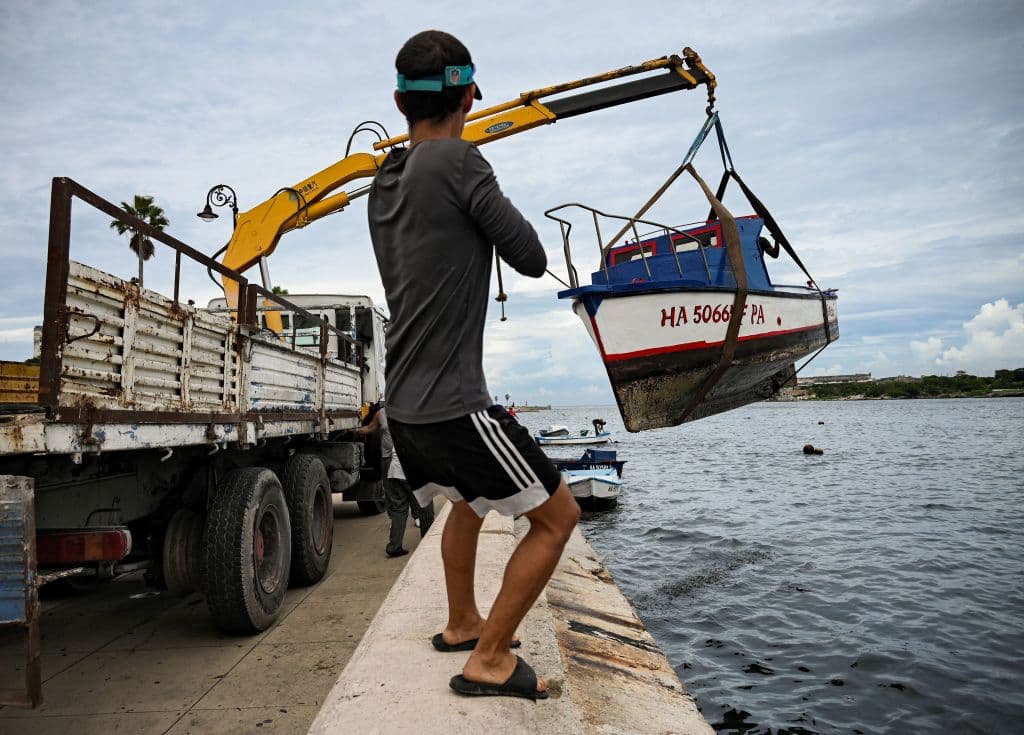 A mna helps pull small boats out of Havana Bay in Havana, on September 26, 2022, as Cuba is expected to bear the brunt of Hurricane Ian. - Tropical storm Ian has strengthened into a Category 1 hurricane as it nears western Cuba, the US National Hurricane Center (NHC) said on Monday. The storm was moving northwest towards Cuba and the Cayman Islands with maximum sustained winds of 75 miles (120 kilometres) per hour, the NHC said. (Photo by Yamil LAGE / AFP) (Photo by YAMIL LAGE/AFP via Getty Images)
