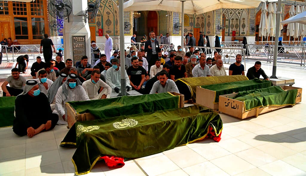 Familiares y allegados rezan frente a varios ataúdes de pacientes con coronavirus que fallecieron en el hospital, víctimas del incendio.