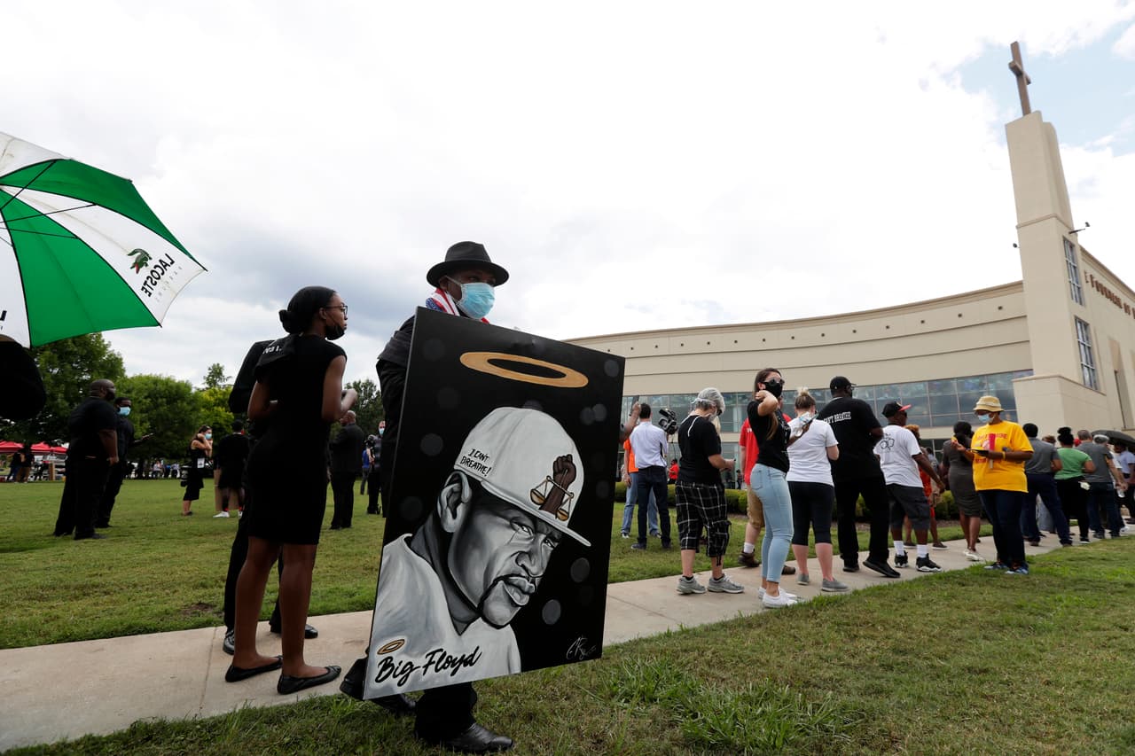 Un grupo de invitados llega con presentes y pancartas a la ceremonia pública para George Floyd.