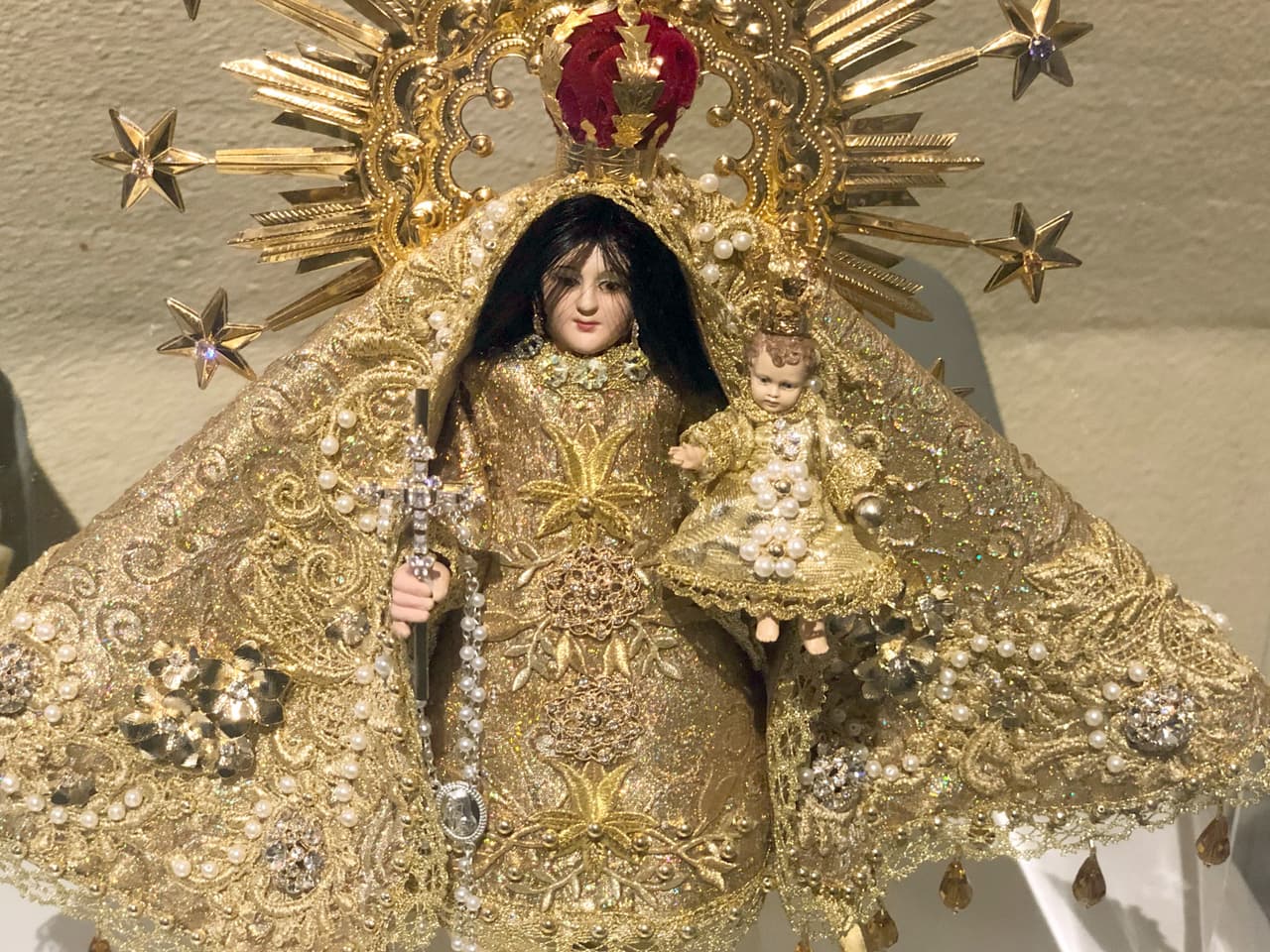 En la obra que está en la Ermita, la Virgen sostiene una cruz en la mano derecha y con el brazo izquierdo carga al niño Jesús. La cruz es un elemento que no estaba en la imagen que llegó a Miami en 1961.