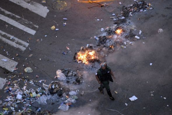 Un miembro de la Guardia Nacional camina al lado del fuego. Los estudiantes llevaron a cabo una manifestación pacífica contra el régimen del mandatario Nicolás Maduro el 12 de febrero de 2014. Motorizados uniformados y con sus caras cubiertas, dispararon contra los manifestantes, matando a dos estudiantes y a un oficial.