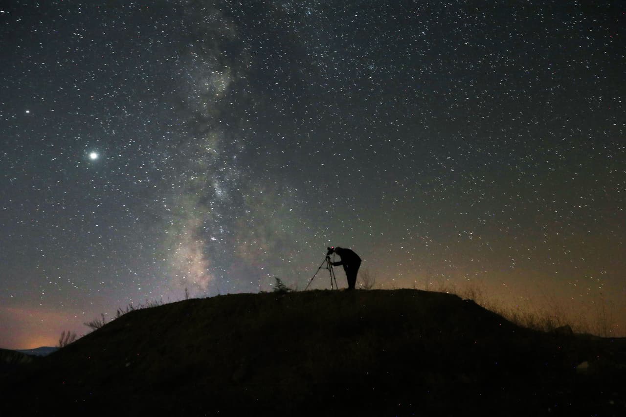 TOPSHOT - A person takes a photo with a camera on a tripod of the Milky Way at Nallihan district, in Ankara, on August 12, 2020. (Photo by Adem ALTAN / AFP) (Photo by ADEM ALTAN/AFP via Getty Images)