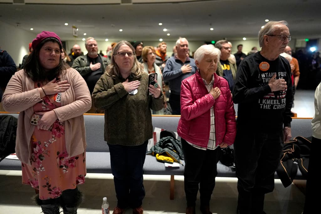 Los votantes recitan el juramento a la bandera en un sitio del caucus en Franklin Junior High en Des Moines, Iowa.