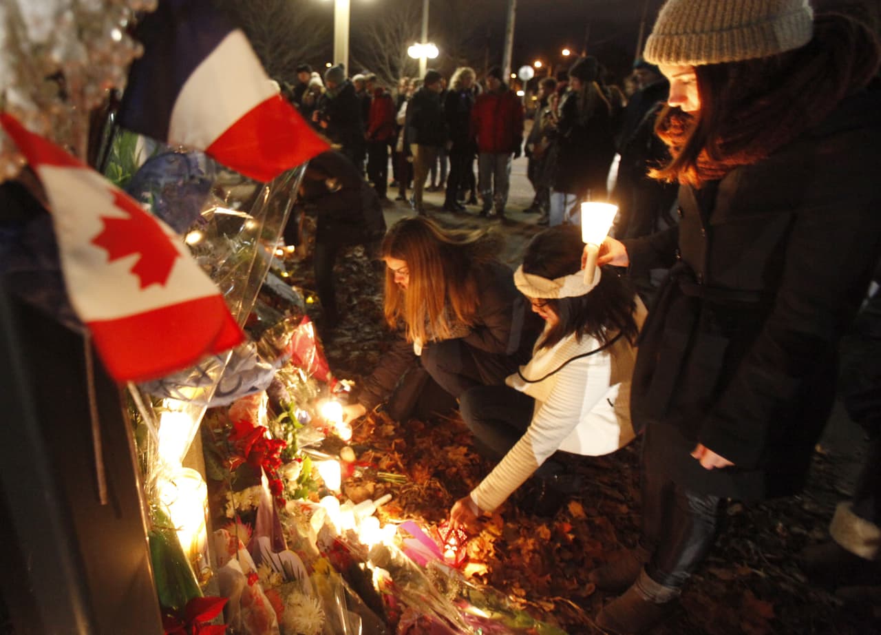 Un grupo coloca velas y flores frente a la embajada de Francia en Ottawa