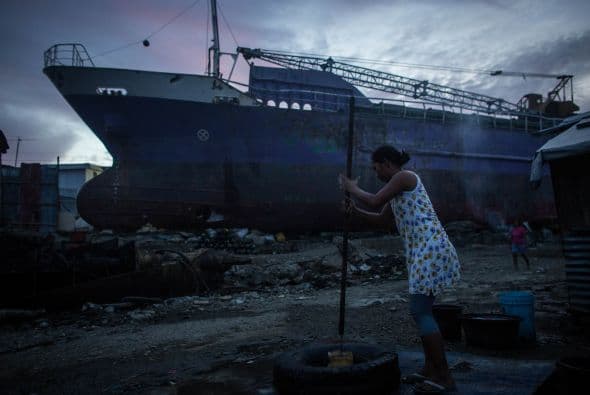 Una mujer saca agua de un improvisado bien en la zona costera de Tacloban, Filipinas.