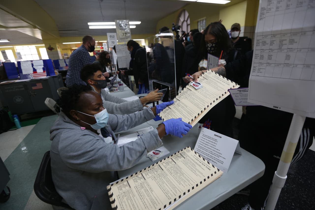 Los comicios se llevan a cabo en la ciudad de Nueva York sin problemas. Trabajadora electoral le da la papeleta a votante en la escuela PS 173 de Washington Heights, Manhattan.