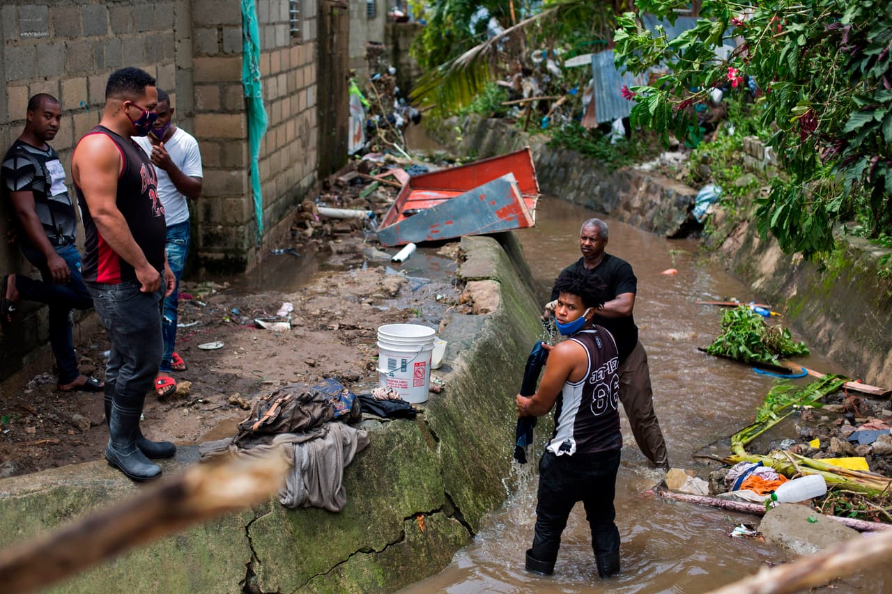 Las personas lavan sus pertenencias en un arroyo después del paso de la tormenta tropical Isaías, con la que las fuertes lluvias provocaron el desbordamiento del río Magua en Hato Mayo.