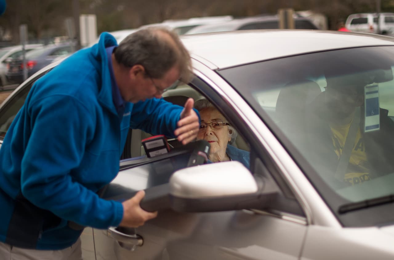 Un funcionario electoral ayuda a una mujer con discapacidad a emitir su voto a través del programa "votación en las esquinas", implementando para quienes no pueden llegar a los recintos.