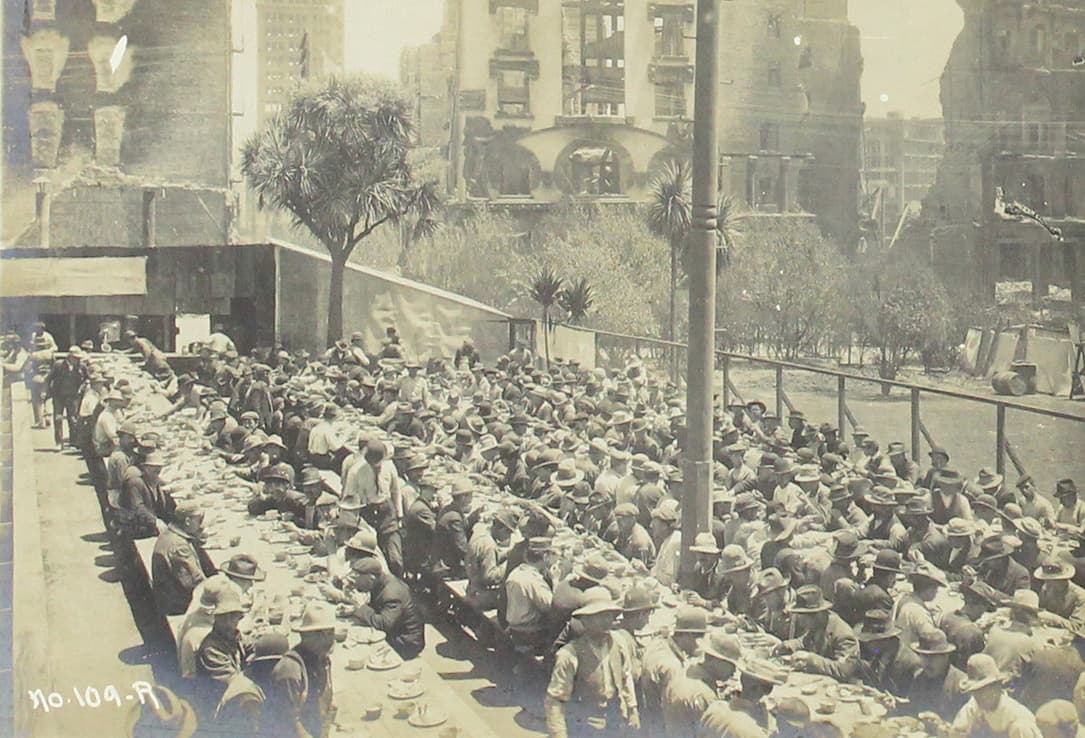 Decenas de personas reciben sus alimentos en un comedor de beneficencia.