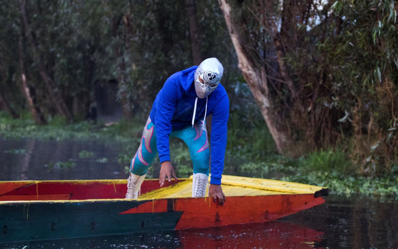 El luchador mexicano Gran Felipe Jr se baja de una "trajinera" para formar parte del evento Chinampalucha. “Como ahorita está lo de la pandemia,
<b>no podíamos hacerlo en un lugar cerrado, donde anteriormente teníamos la arena, entonces decidimos llevar esto a este lugar mágico que son las chinampas de Xochimilco”</b>, dicen.