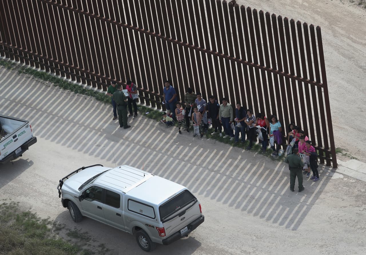 Una hilera de familias cerca de McAllen, Texas, son inspeccionados por la Patrulla Fronteriza. Con el cambio de política, los adultos recibirán cargos por entrada ilegal y pasarán a detención criminal, lo que los separará de los menores.