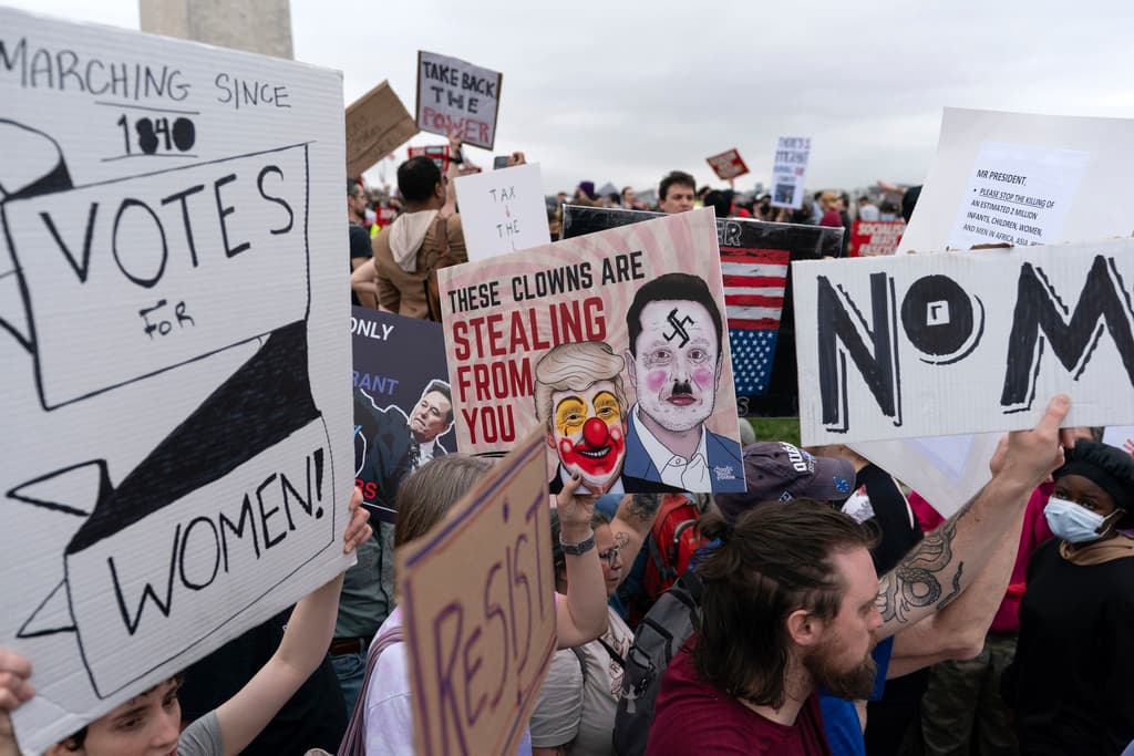 Demonstrators carry signs during the "Hands Off!" protests against President Donald Trump and Elon Musk at the Washington Monument in Washington, Saturday, April 5, 2025. (AP Photo/Jose Luis Magana)
