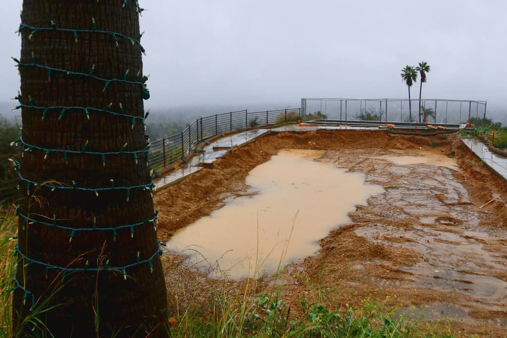 Rain water from a winter storm collects on a property that was destroyed by the Eaton Fire almost a year ago, on Wednesday, Dec. 24, 2025, in Altadena, Calif. (AP Photo/Ty ONeil)
