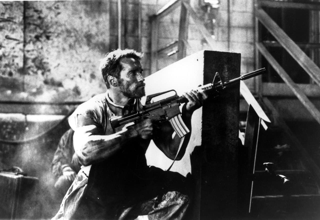 Schwarzenegger sosteniendo una ametralladora en una escena de la película Running Man de 1987.