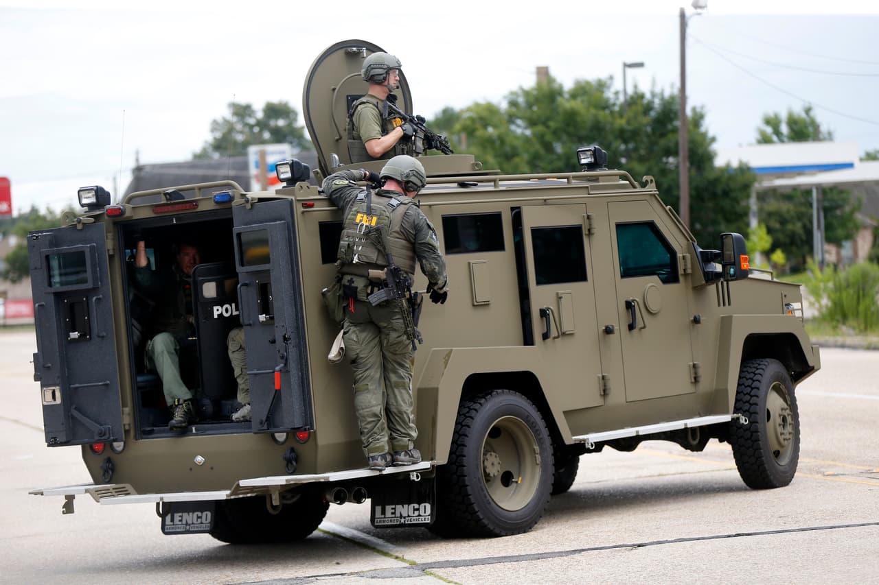 Elementos del FBI patrullan el perímetro de la escena del crimen en un vehículo blindado.