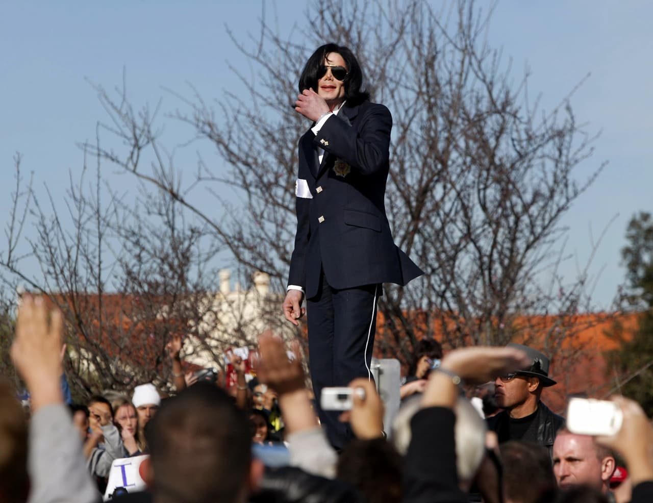 En esta foto del 16 de enero del 2004, Michael Jackson, montado sobre una limusina, saluda a sus fans tras la lectura de sus cargos por abuso de menores en un tribunal en Santa María, California.