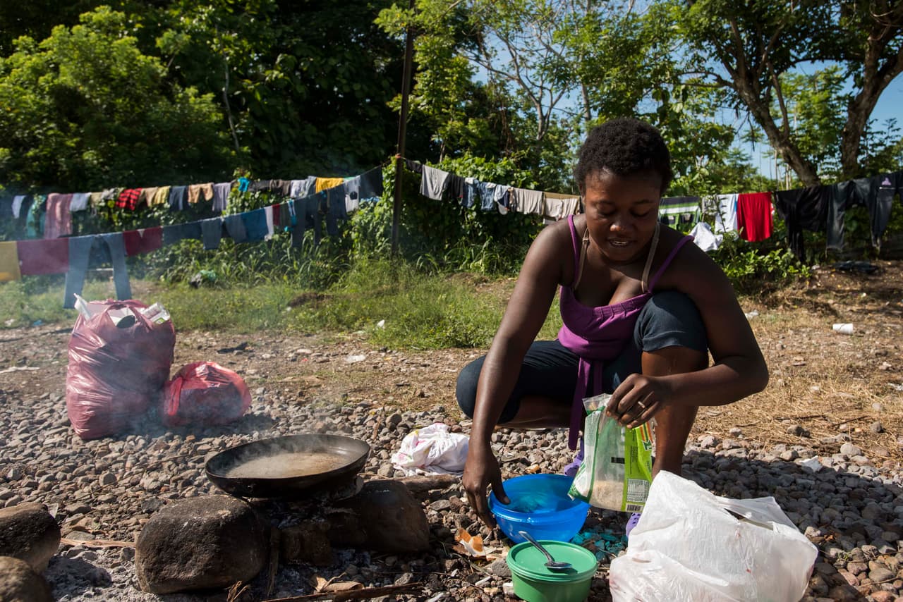 Los inmigrantes lamentan las malas condiciones de los campamentos donde viven. En la imagen, Mega cocina arroz en una fogata improvisada de piedras, palos y carbón.