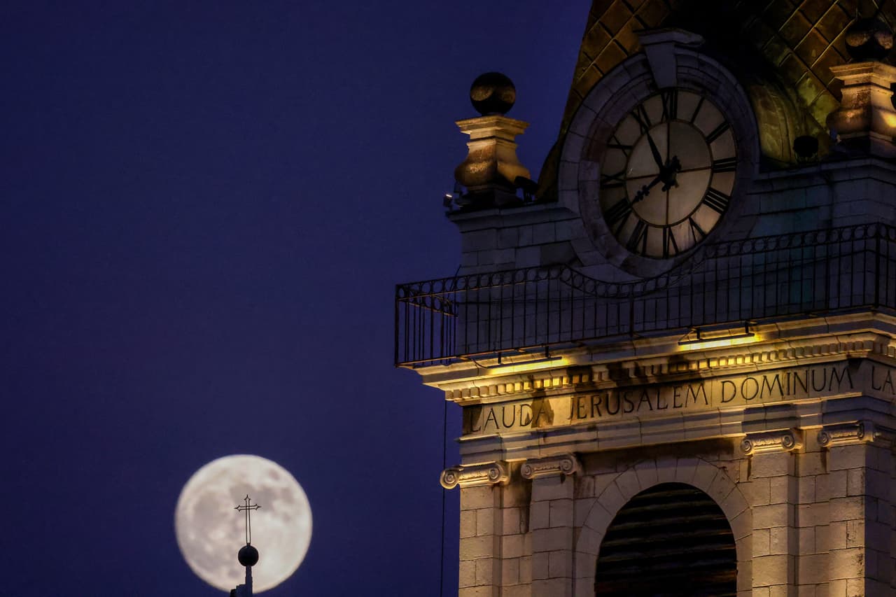 La luna creciente se eleva detrás de una cruz en una iglesia de la ciudad vieja de Jerusalén el 12 de julio de 2022, un día antes de la "superluna de ciervo" de julio.