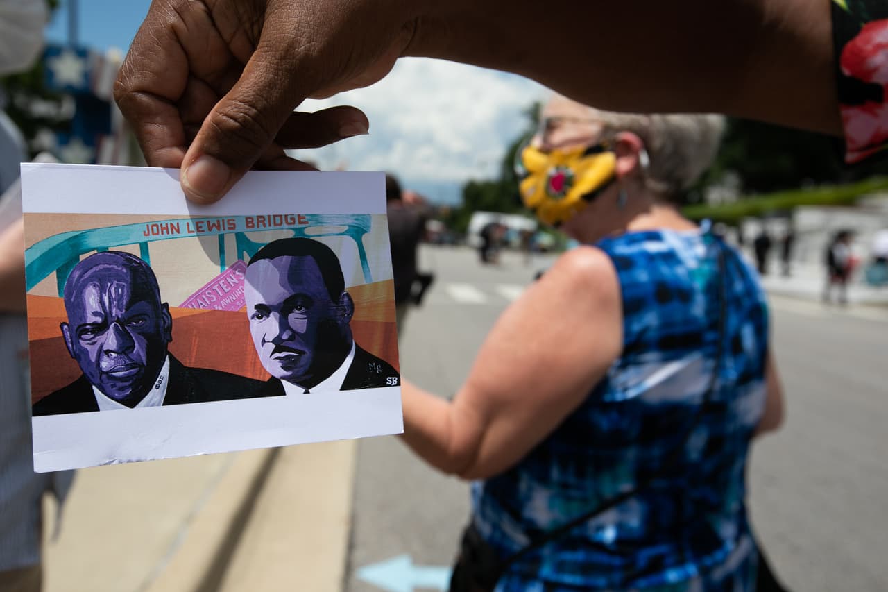 Una de las personas que se acercó hasta el puente para ser parte del homenaje al exrepresentante sostiene un dibujo con dos de los más importantes activistas por los derechos civiles en Estados Unidos, John Lewis y
<a href="https://www.univision.com/shows/noticiero-univision/recordando-a-martin-luther-king-jr-video">Martin Luther King, Jr<b>.</b></a>
<b> </b>