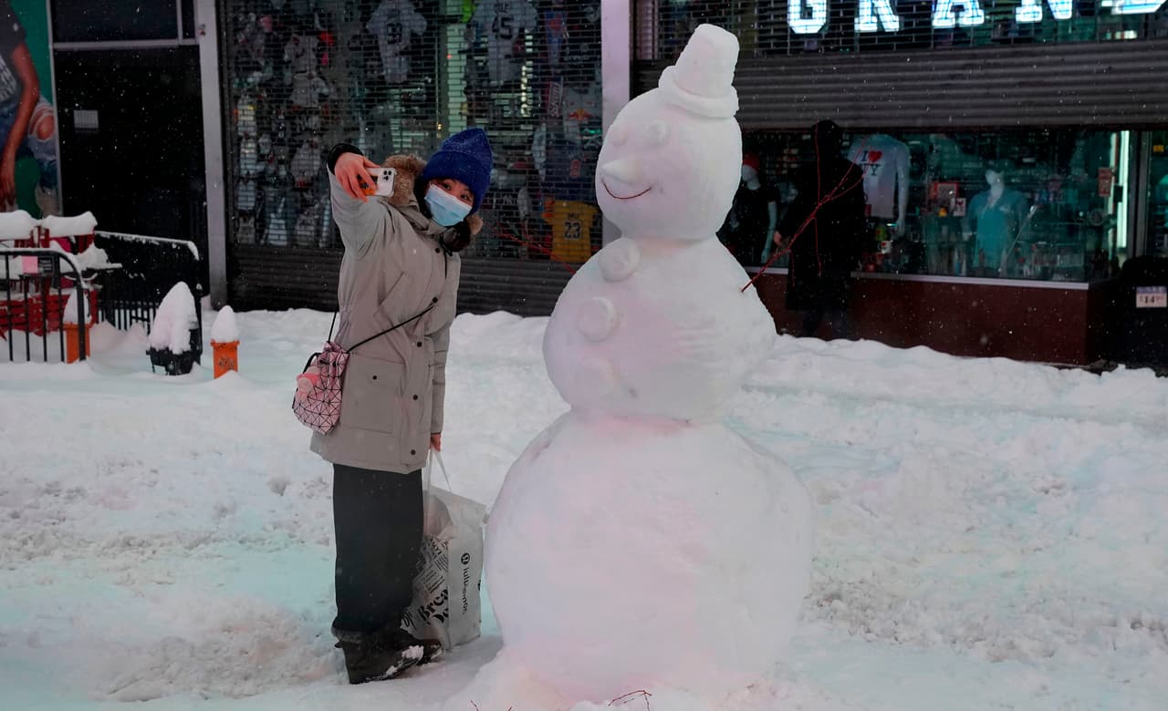 Una mujer se toma un selfie con un muñeco de nieve en Times Square