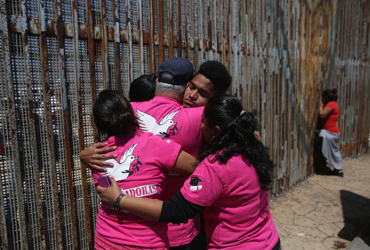 Relatives meet at the border fence separating the United States and Mexico. The Border Patrol allows families to meet at weekends.