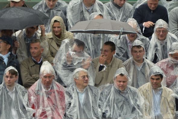 Las personas se protegen de la lluvia en el estadio Roland Garros, París.