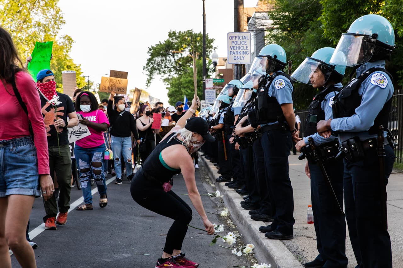 Un grupo de manifestantes pone flores a los pies de un grupo de oficiales durante las protestas del 6 de junio en Chicago.
