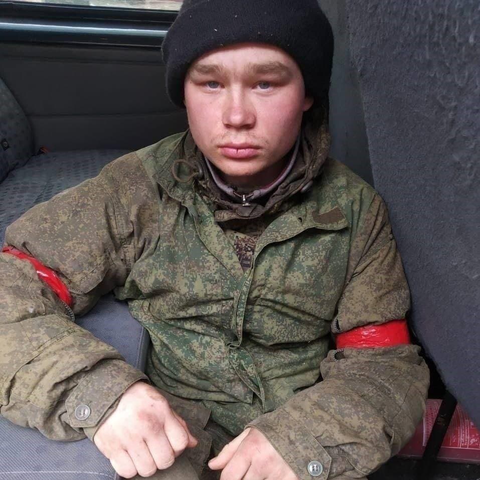 Este joven militar ruso de entre 18 y 19 años fue capturado por tropas ucranianas durante la invasión. Las cintas rojas en sus brazos lo identifican como un prisionero de guerra.